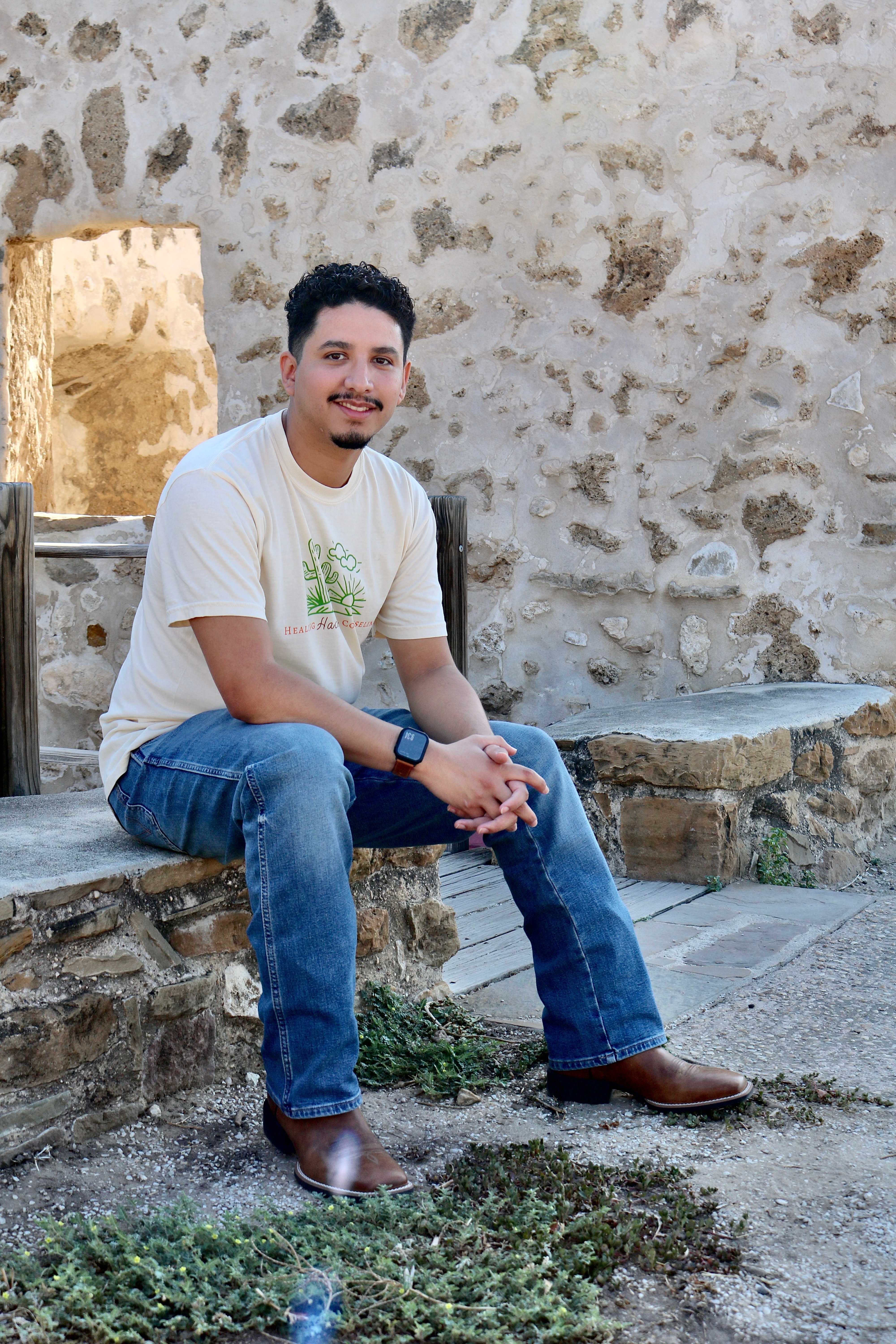 Jorge Humberto Ortiz seated beside a warm stone wall